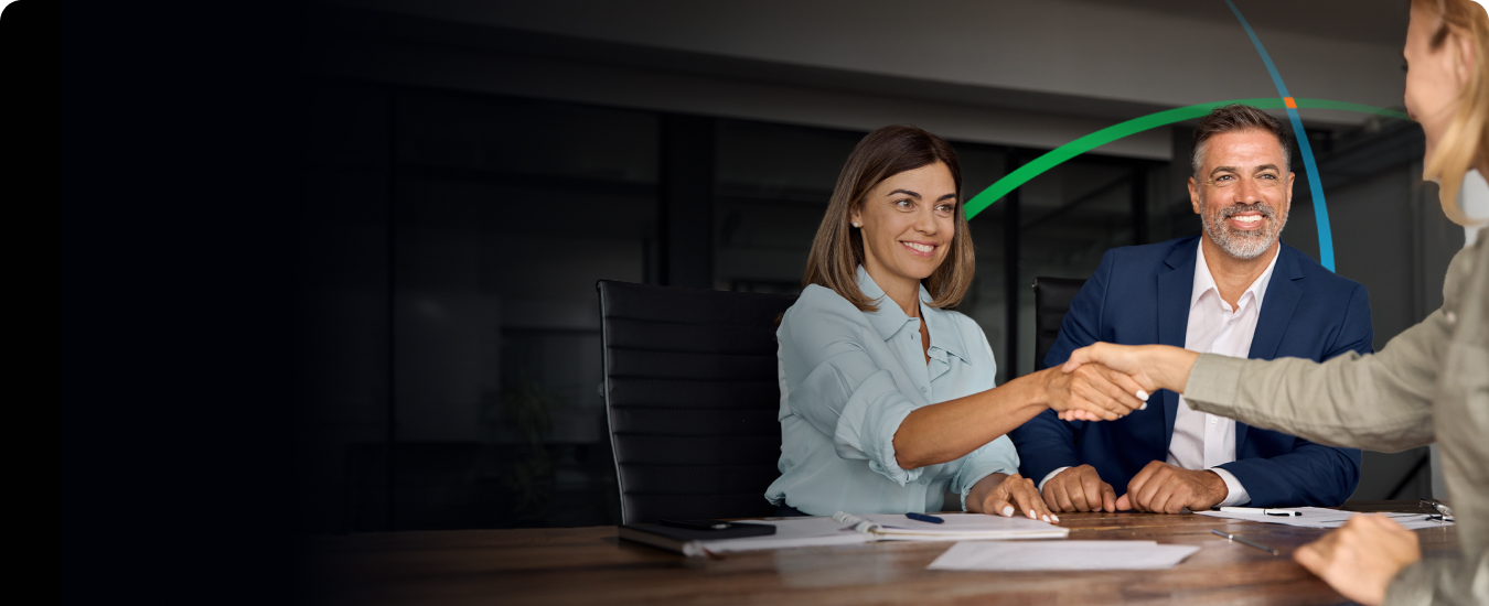 banner showing two women and a man shaking hands across a table while sitting in a conference room