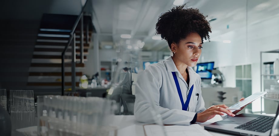 a medical professional working on her laptop while holding another mobile device
