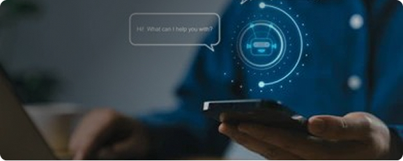 a man in a blue shirt typing on a laptop keyboard while interacting with an AI assistant on his phone
