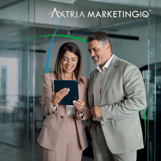 a man and a woman standing in a modern office space and smiling while looking at a tablet screen