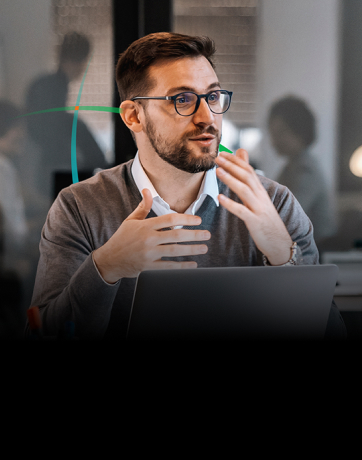 banner showing a man talking to another person while sitting in front of a laptop in a modern office setting
