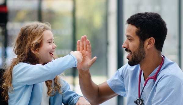 a smiling healthcare professional playing with a child