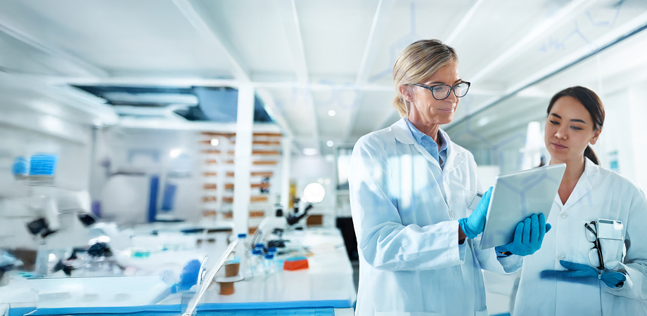 two medical professionals having a discussion in a lab while looking at a tablet screen