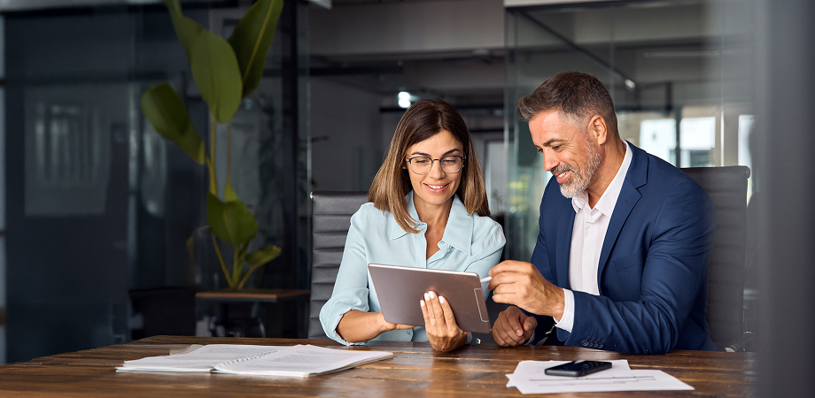 two business professionals having a discussion while looking at a tablet screen