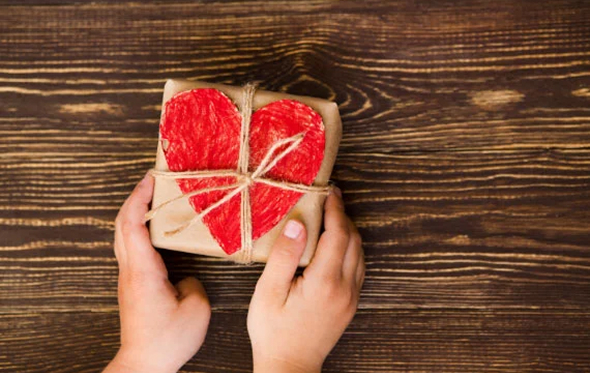 hands holding a package with a hand-drawn heart on the cover
