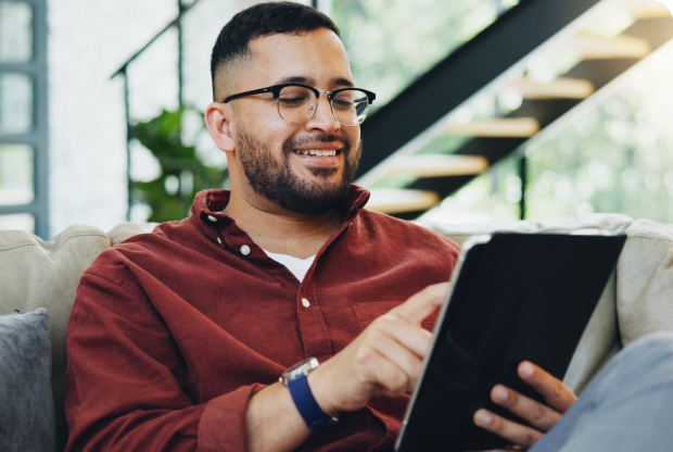 a smiling man in a red shirt interacting with his tablet device