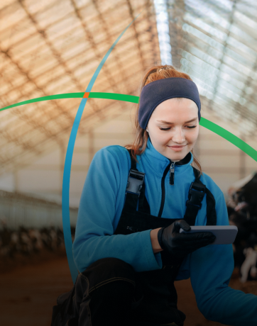 banner showing a smiling woman looking at her phone while feeding a cow in a shed