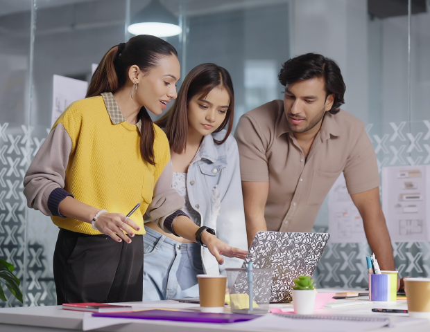 three young professionals having a discussion while looking at a laptop screen