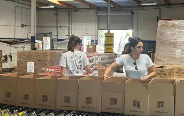 two women filling boxes with essential food supplies